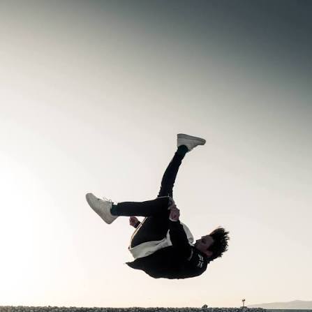 Parkourutövare gör en backflip mot kvällshimlen